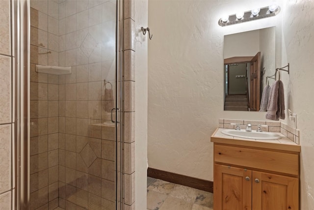 bathroom featuring a shower stall, vanity, baseboards, and a textured wall