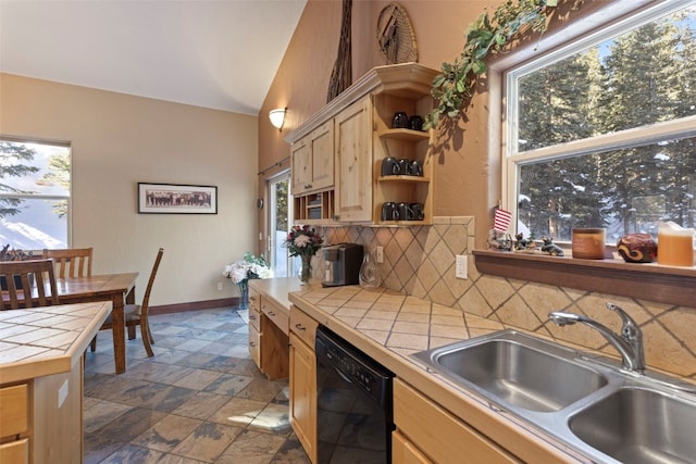 kitchen with black dishwasher, decorative backsplash, tile countertops, light brown cabinets, and a sink