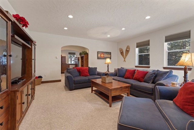 living room with arched walkways, recessed lighting, light carpet, a textured ceiling, and baseboards