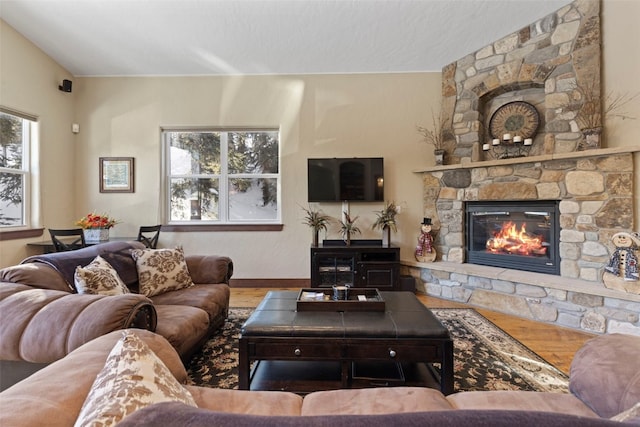 living room featuring wood finished floors and a stone fireplace