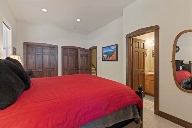 bedroom featuring arched walkways, recessed lighting, light colored carpet, connected bathroom, and baseboards