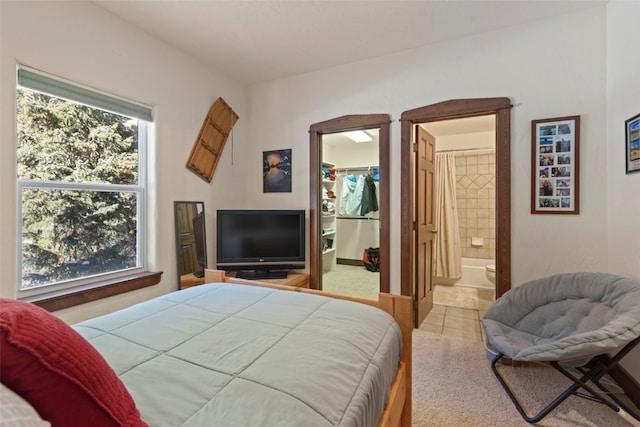 tiled bedroom with a walk in closet, a closet, and ensuite bathroom