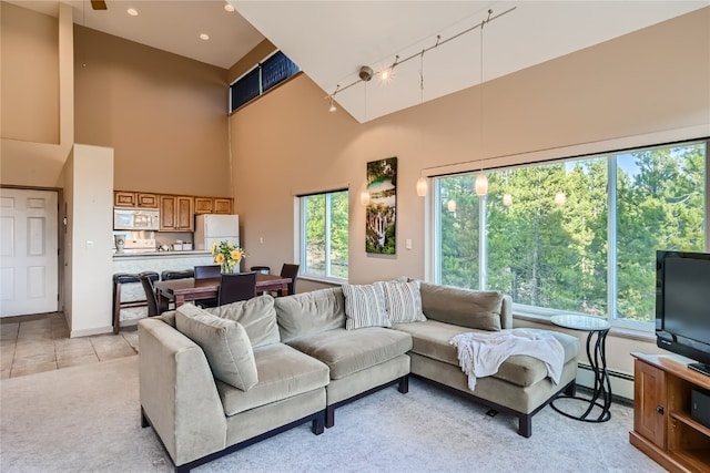 living room featuring a towering ceiling, track lighting, and baseboard heating