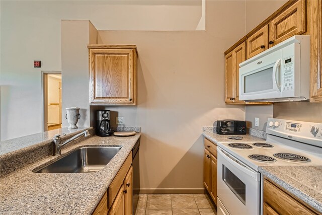 kitchen with light stone countertops, light tile patterned floors, white appliances, and sink