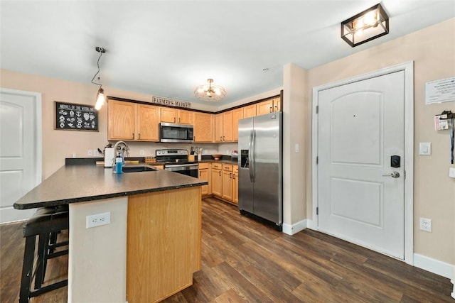 kitchen featuring sink, stainless steel appliances, dark wood-type flooring, kitchen peninsula, and a breakfast bar