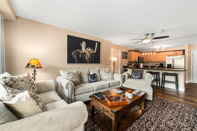 living room featuring dark hardwood / wood-style floors, ceiling fan, and sink