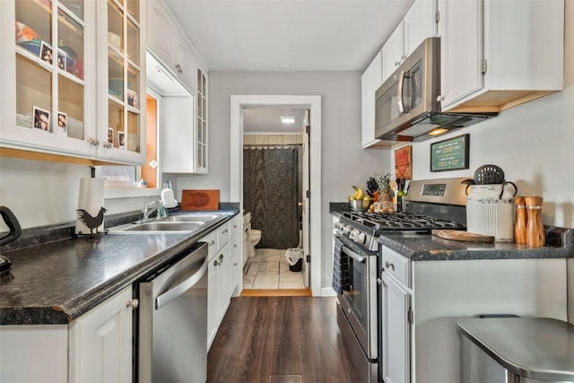 kitchen with dark countertops, white cabinetry, appliances with stainless steel finishes, and a sink