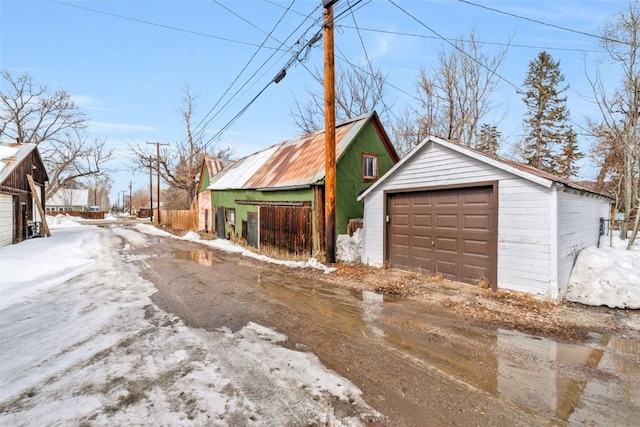 snow covered garage with a detached garage and fence