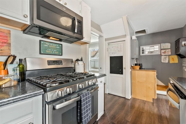 kitchen with stainless steel appliances, dark countertops, white cabinetry, and dark wood-type flooring