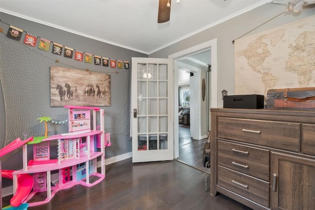 rec room featuring dark wood-style floors, crown molding, baseboards, and a ceiling fan