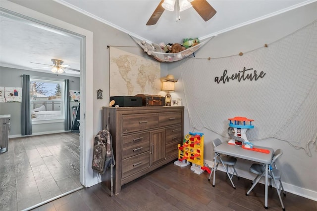 playroom with baseboards, crown molding, a ceiling fan, and dark wood-type flooring