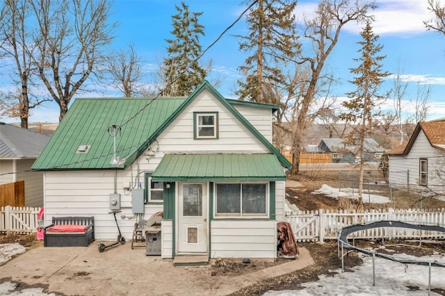 back of property with metal roof, fence, and a gate