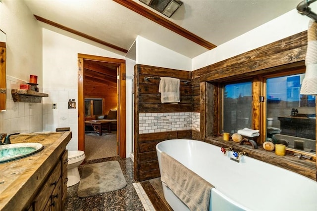 bathroom with vaulted ceiling, toilet, a bathtub, vanity, and tile walls