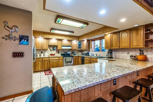 kitchen with stainless steel range with electric cooktop, white dishwasher, light tile patterned flooring, kitchen peninsula, and a breakfast bar area