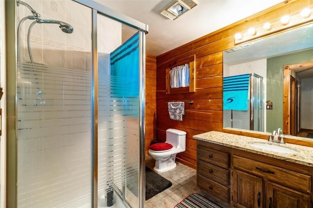 bathroom featuring vanity, a shower with door, wooden walls, tile patterned flooring, and toilet