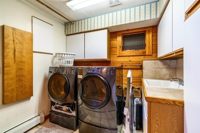 washroom with cabinets, a textured ceiling, a baseboard heating unit, sink, and washing machine and dryer