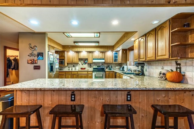 kitchen with sink, stainless steel appliances, a kitchen breakfast bar, tasteful backsplash, and kitchen peninsula