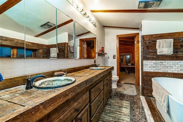 bathroom with a tub to relax in, tasteful backsplash, vanity, toilet, and lofted ceiling