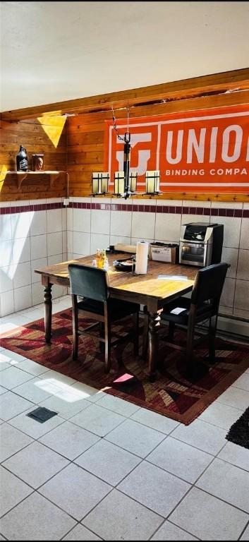 dining area with tile patterned flooring and wood walls