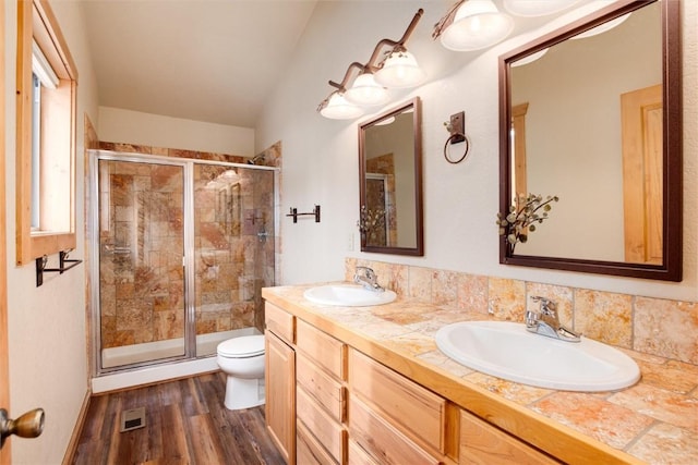 bathroom with wood-type flooring, vanity, toilet, and a shower with shower door