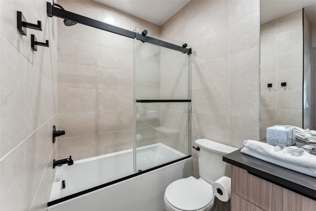 bathroom featuring bath / shower combo with glass door, tile walls, vanity, and toilet