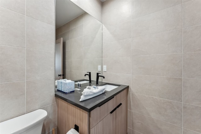 half bath featuring vanity, toilet, and tile walls