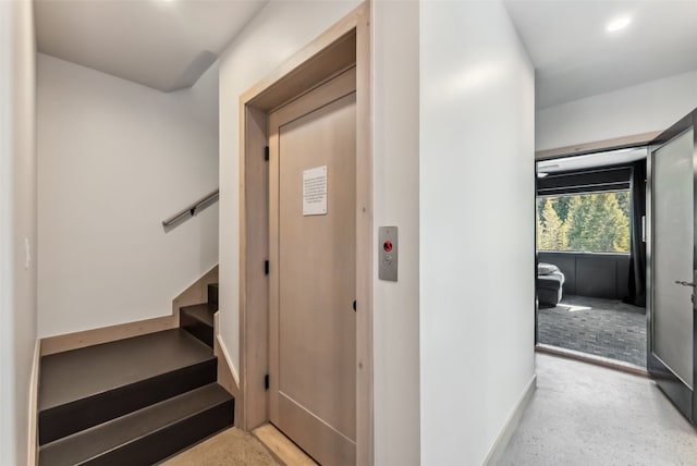 stairway featuring baseboards and elevator