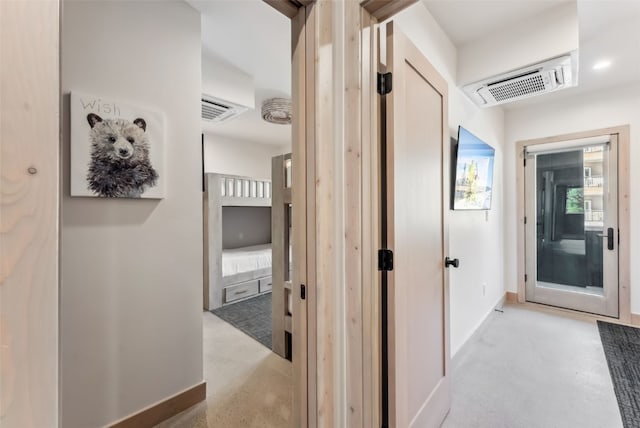 hallway featuring baseboards, visible vents, and finished concrete floors