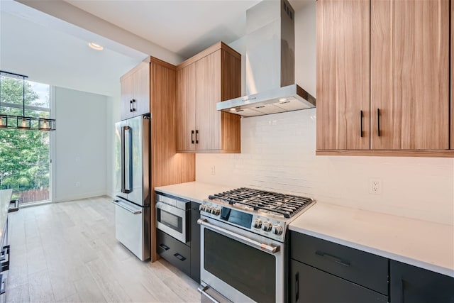 kitchen featuring decorative backsplash, light hardwood / wood-style floors, wall chimney range hood, and high end appliances