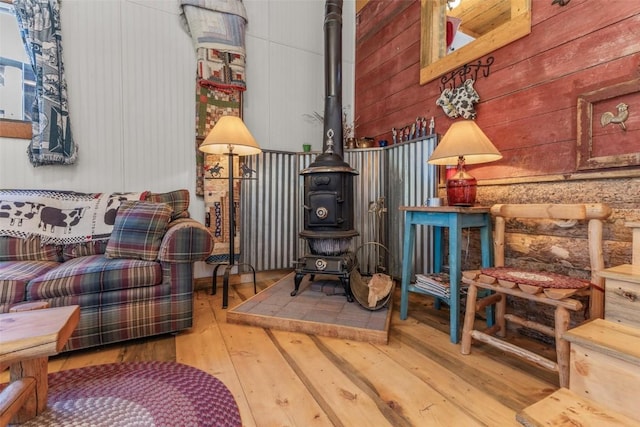 sitting room featuring hardwood / wood-style flooring, a wood stove, and wooden walls