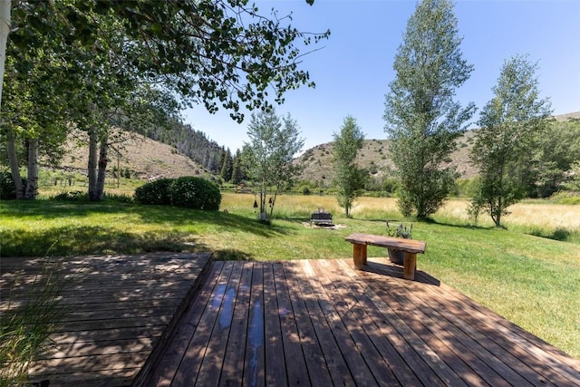 view of home's community featuring a lawn, a deck with mountain view, and an outdoor fire pit