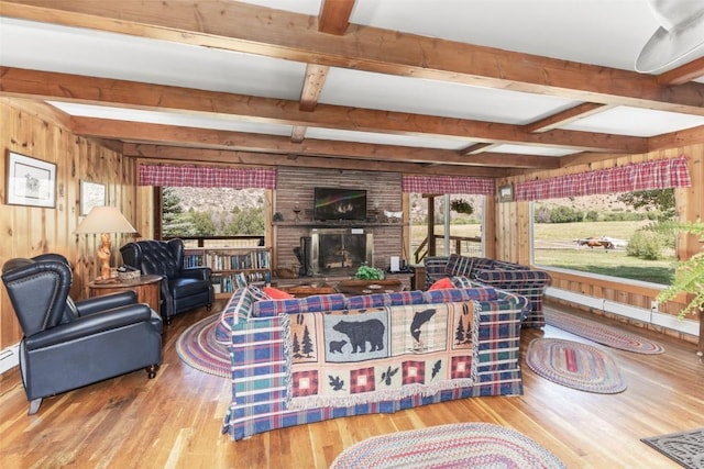 living room with beam ceiling, hardwood / wood-style flooring, a healthy amount of sunlight, and a brick fireplace