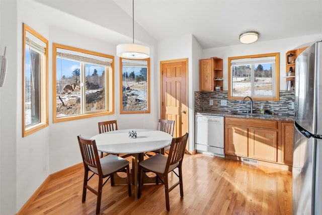 dining room featuring lofted ceiling, sink, and light hardwood / wood-style flooring