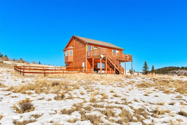 snow covered rear of property with a wooden deck