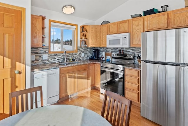 kitchen featuring lofted ceiling, appliances with stainless steel finishes, sink, and stone counters