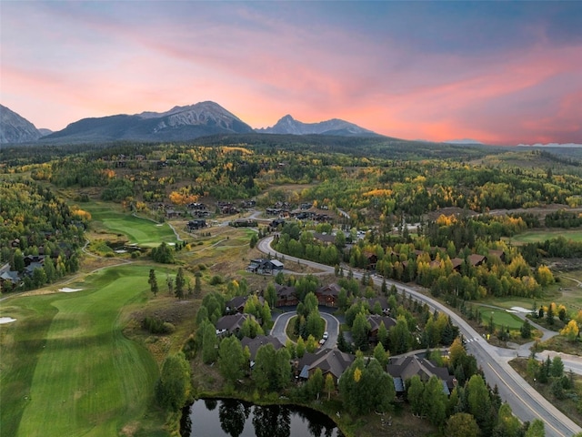 aerial view at dusk featuring a water and mountain view