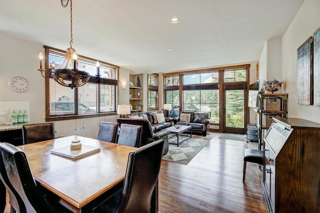 dining space with light hardwood / wood-style flooring, built in features, and a notable chandelier