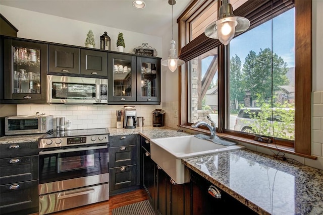 kitchen featuring pendant lighting, light stone counters, and appliances with stainless steel finishes