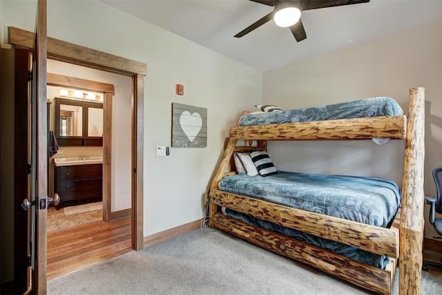 carpeted bedroom with ensuite bath and ceiling fan