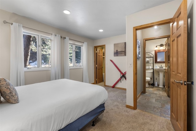 bedroom featuring connected bathroom and light carpet