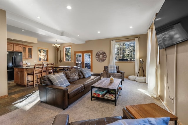 carpeted living room featuring beamed ceiling and a chandelier