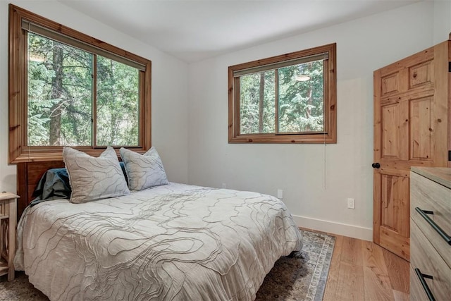 bedroom with light wood finished floors and baseboards