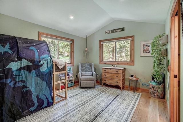 living area featuring lofted ceiling, wood finished floors, and baseboards