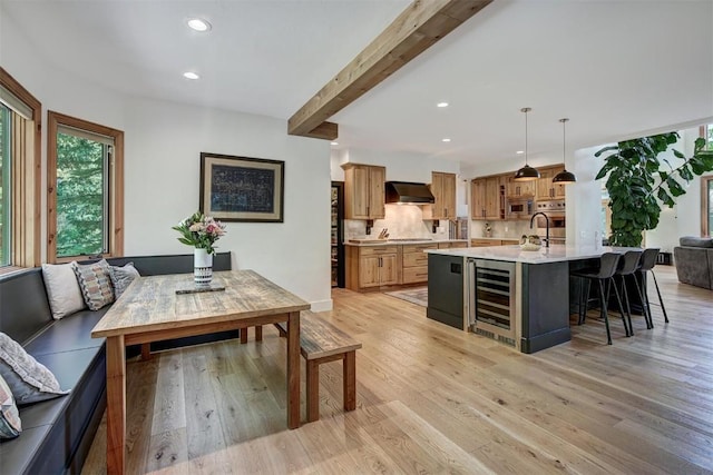 interior space with light wood finished floors, wine cooler, beam ceiling, and recessed lighting