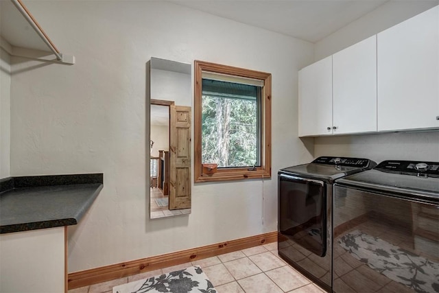 clothes washing area featuring light tile patterned flooring, washing machine and clothes dryer, cabinet space, and baseboards