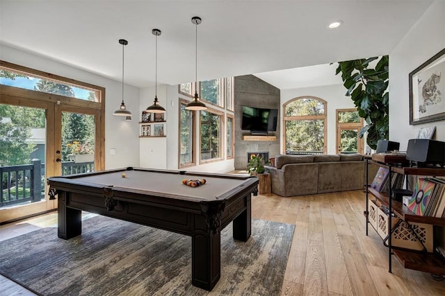 game room featuring a healthy amount of sunlight, light wood finished floors, a fireplace, and french doors