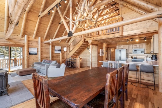 dining space featuring a wood stove, wooden ceiling, high vaulted ceiling, and wood walls