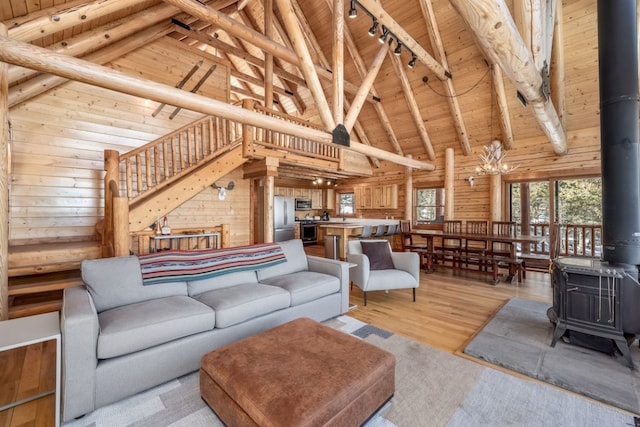 living room featuring light wood finished floors, wood ceiling, a wood stove, wood walls, and track lighting