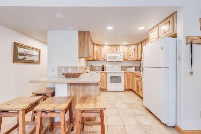 kitchen with light tile patterned flooring, white appliances, kitchen peninsula, and light brown cabinetry