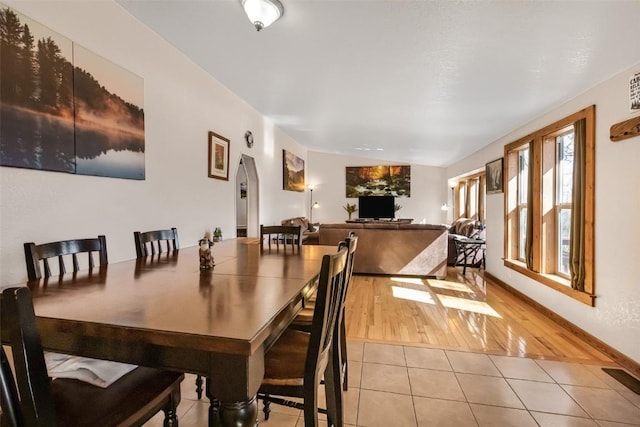 dining room featuring arched walkways, baseboards, and light tile patterned floors